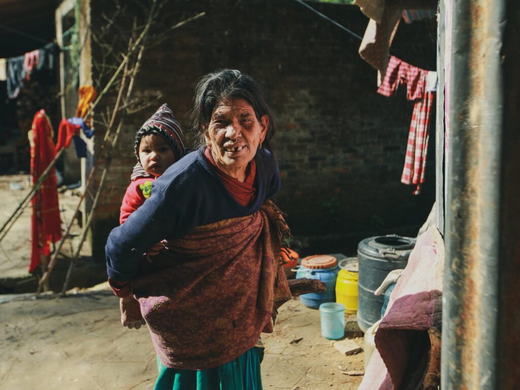 elderly woman with child on back in poor village