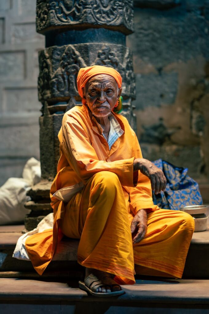 elderly man in yellow gown sitting on floor in temple